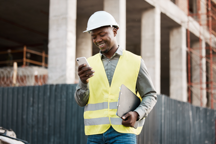 Shot of a young businessman using his smartphone while on a construction site